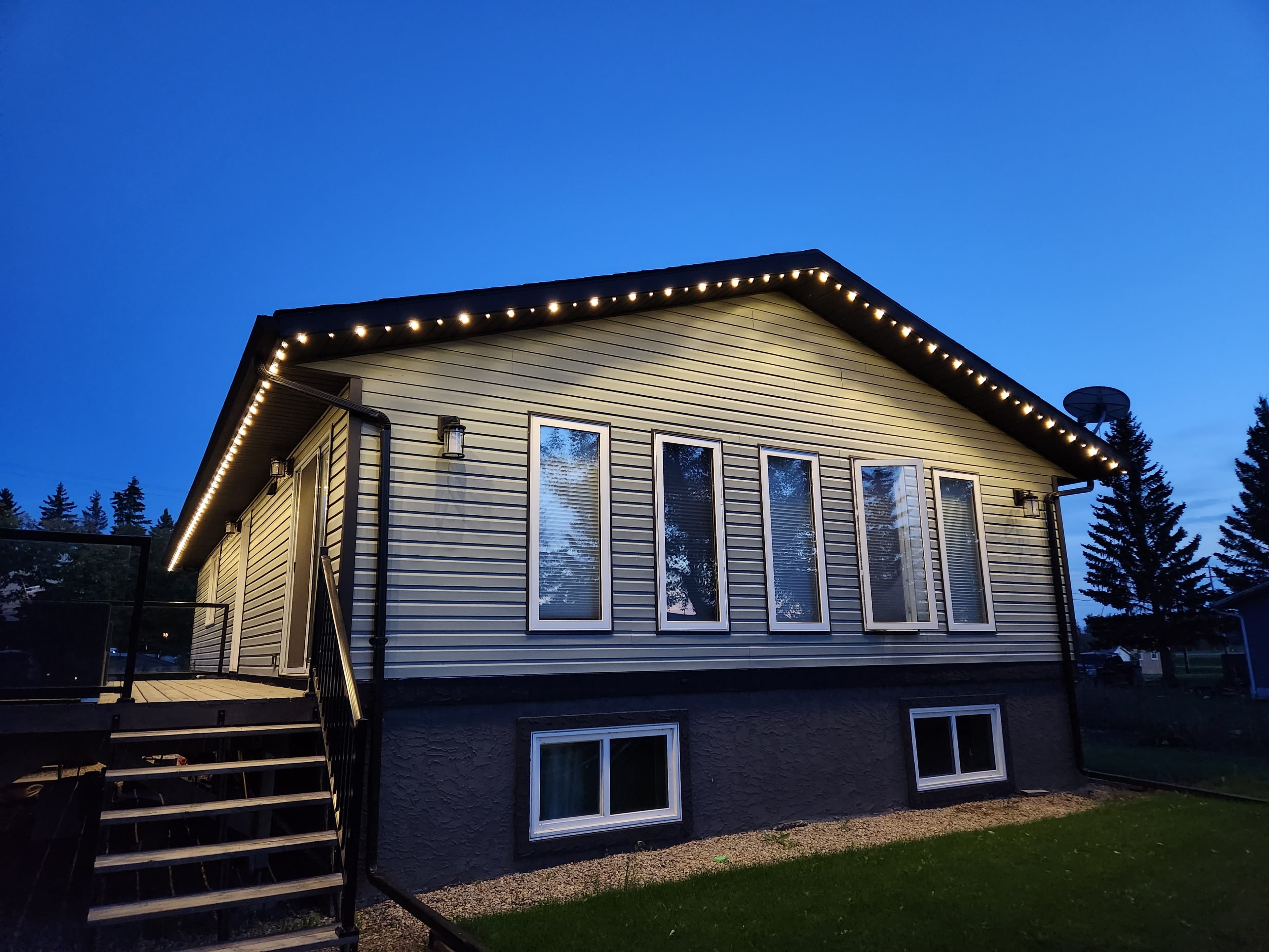 Permanent LED roofline lighting set to warm white on a Halton home at twilight
